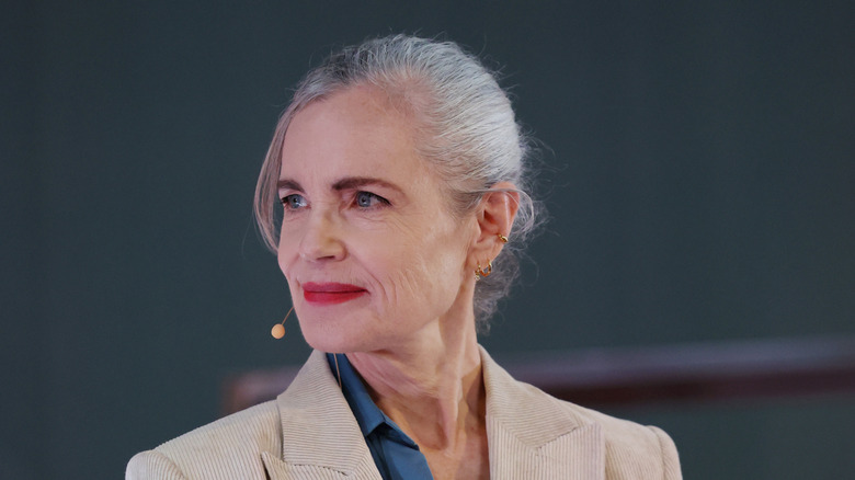Elizabeth McGovern smiles wearing a beige blazer and red lipstick