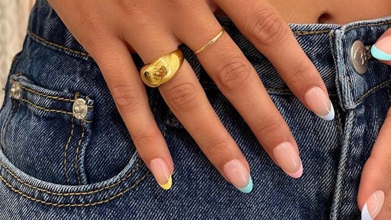 Closeup of hand with rainbow pastel French manicure