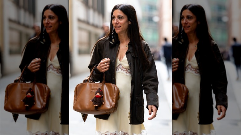 A woman walks down the street in Paris carrying a leather bag