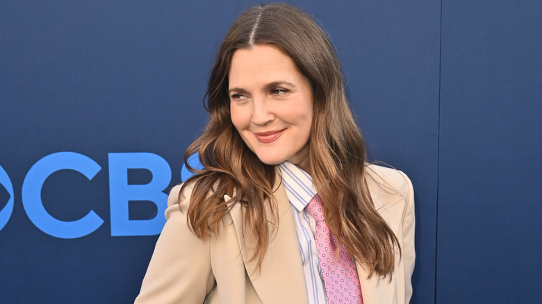 Drew Barrymore smiling, wearing a tan suit with her hair down.