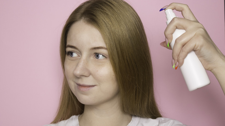 woman spraying dry shampoo in her hair