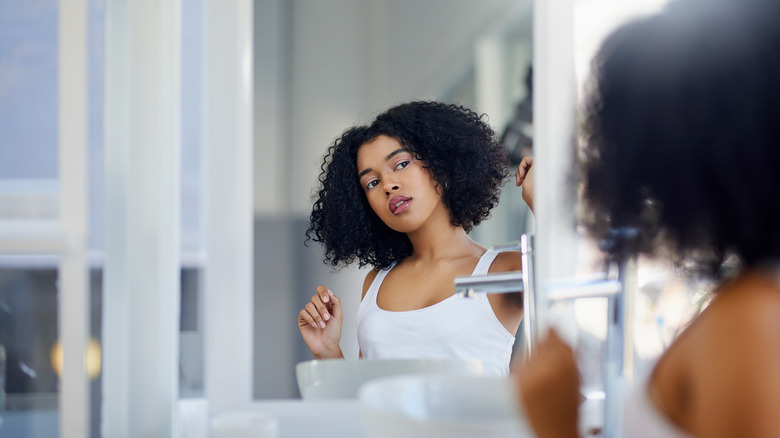Curly haired woman looking at her hair in a mirror