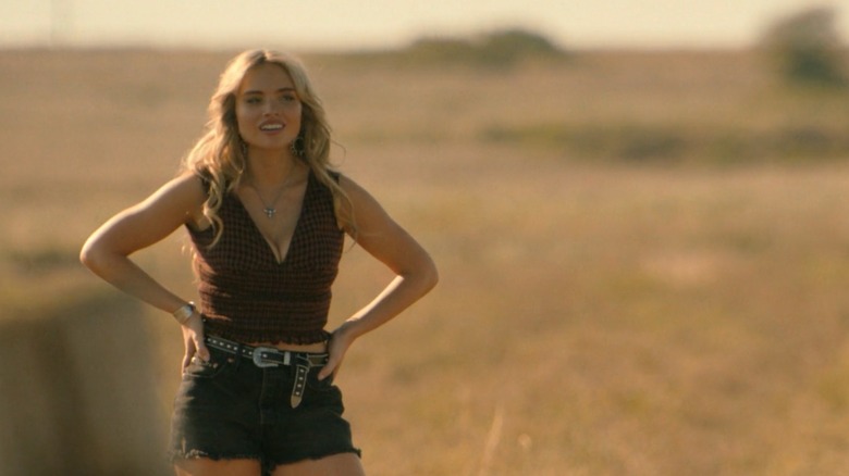 Oreana Jackson stands with her hands on her hips wearing black shorts and a checked vest in a scene from "Dutton Ranch."