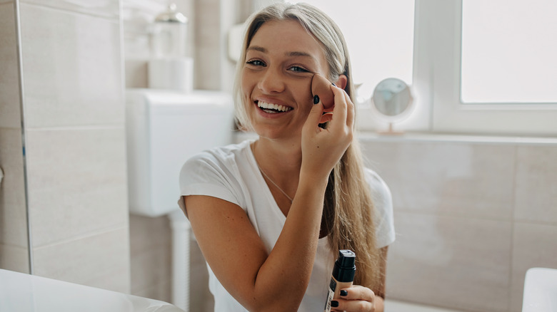 smiling woman applying foundation