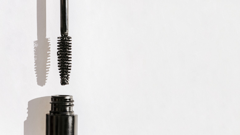Mascara wand above black bottle