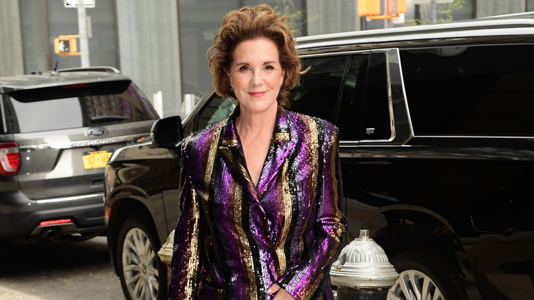 Elizabeth Perkins softly smiling  while in New York City wearing a shimmering sequin suit.