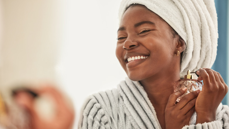 cheerful woman sprays perfume
