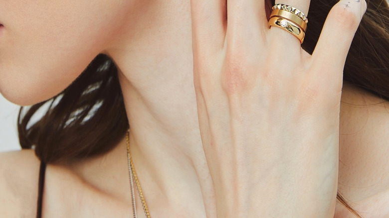 A woman wearing stacked gold wedding and engagement rings