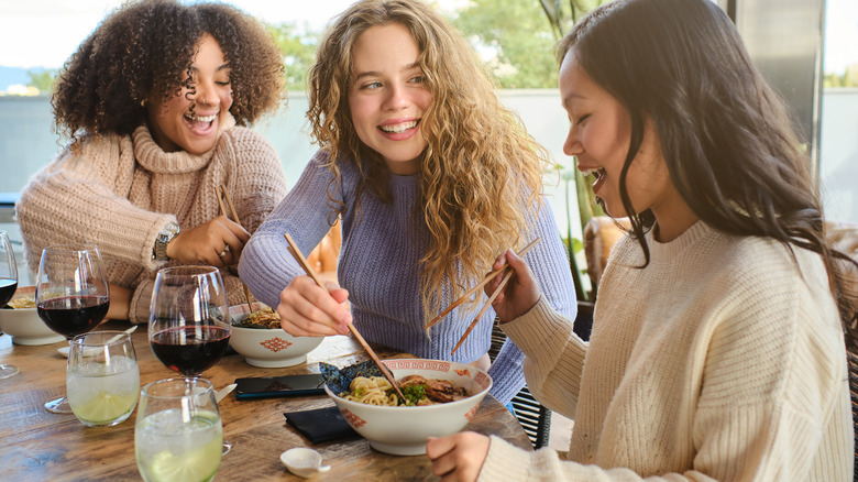 Smiling friends eating ramen together