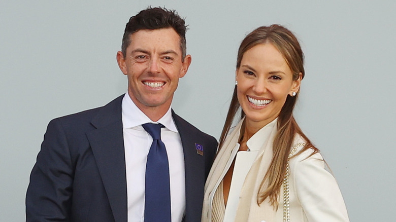 Rory McIlroy and wife Erica Stoll smile while posing together for a photo