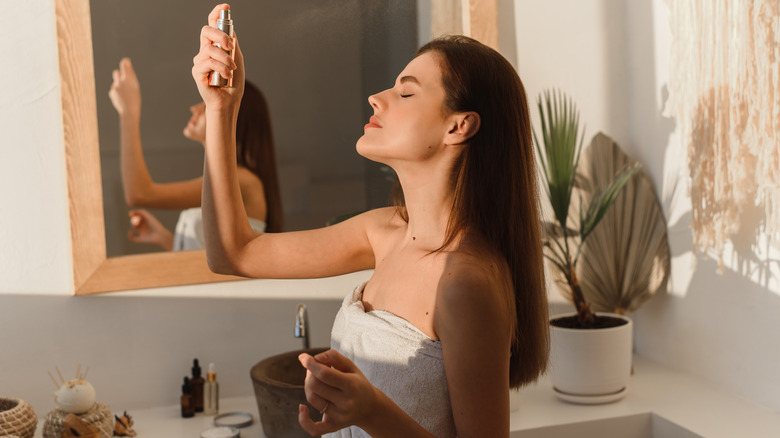 Woman sprays face with essence 