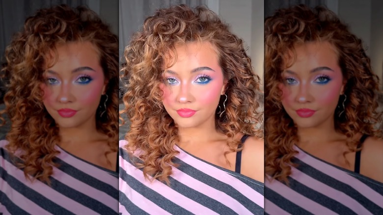 A woman with '80s hair and makeup taking a selfie