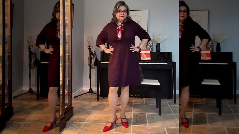 A woman with a deep purple dress, bright red shoes, and a printed scarf.