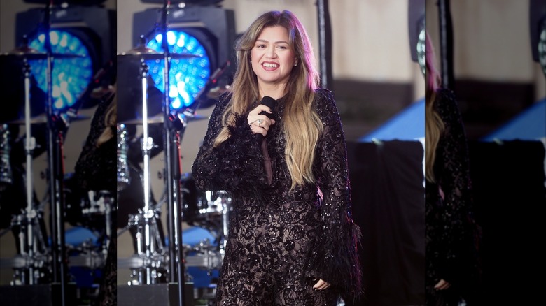 Kelly Clarkson singing onstage in a bodysuit