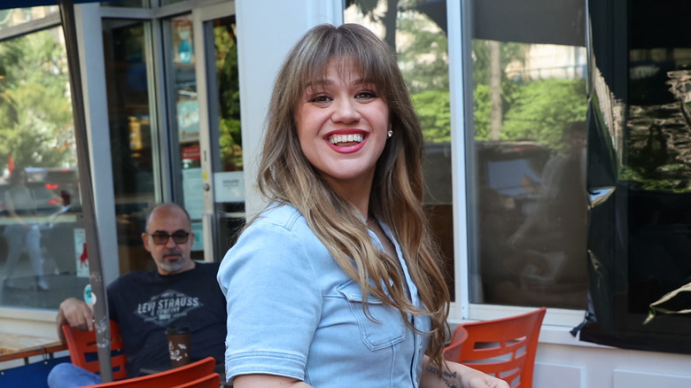 Kelly Clarkson smiles for a photo while walking outside
