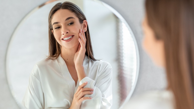 woman mirror examining skin