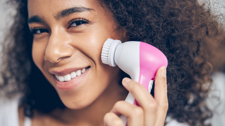 Woman using facial cleansing brush