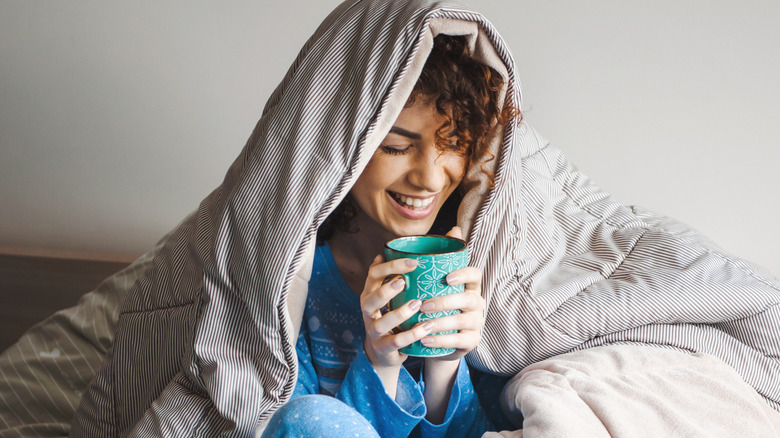 woman holding a mug with a blanket wrapped around her