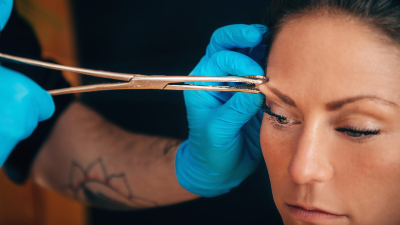 Woman getting eyebrow pierced
