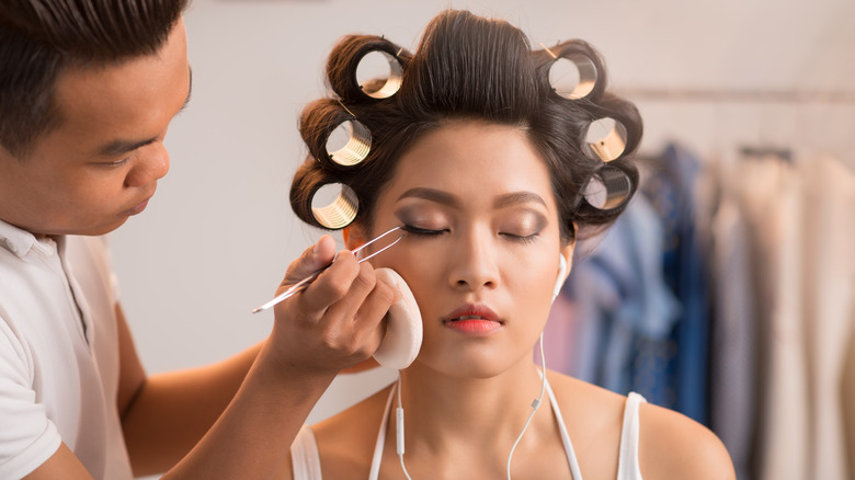 Man applies fake lashes to woman's eye