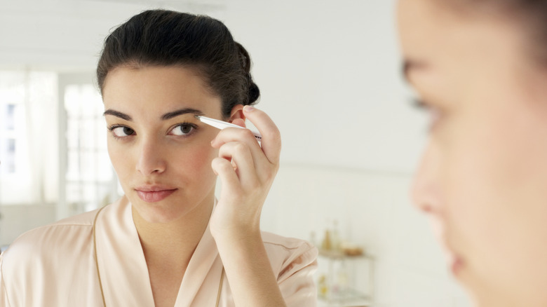 Woman tweezing her eyebrows