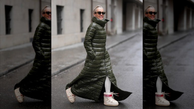 A woman wearing a long green coat with a funnel neck.