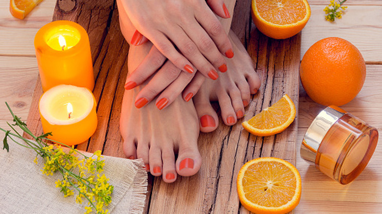Hands and toes with orange nail polish