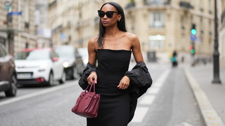 Emilie Joseph in a black strapless bodycon dress and with a jacket and burgundy bag in Paris in April 2026