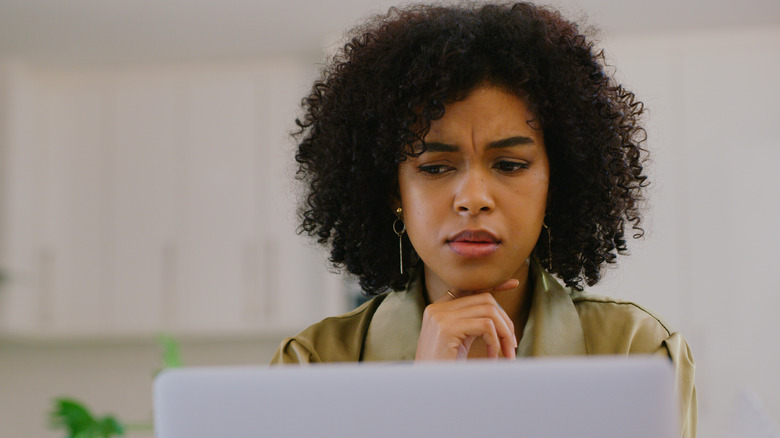 Woman looking at laptop confused