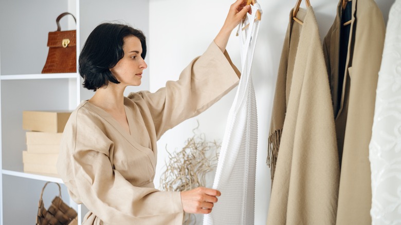 A woman looks at clothing while considering whether to buy it