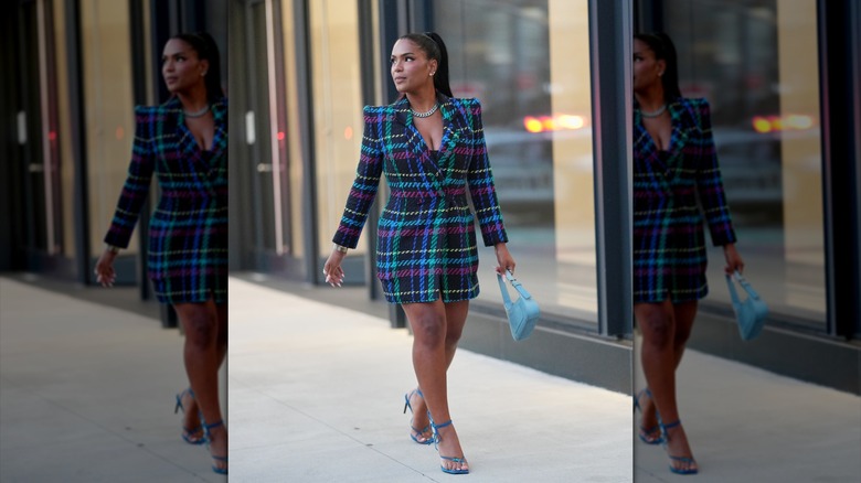 A woman in a plaid coat and blue shoes with a blue handbag