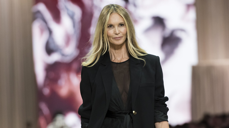 Elle MacPherson walks the runway in a sheer black dress paired with an oversized blazer