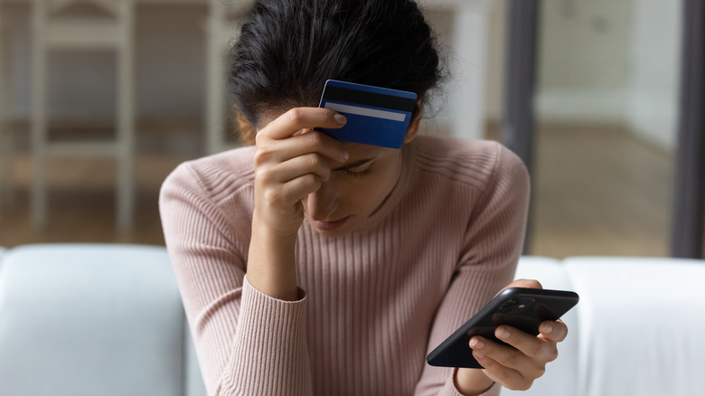 Stressed woman holds credit card