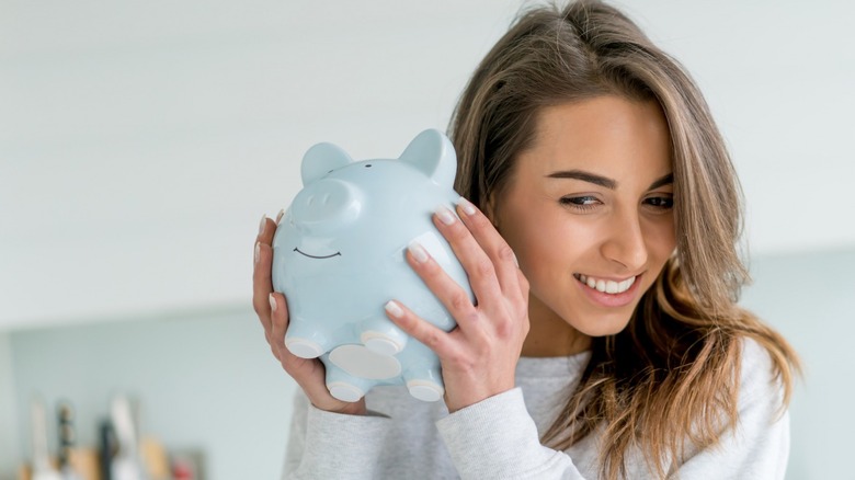 Woman holding up blue piggy bank