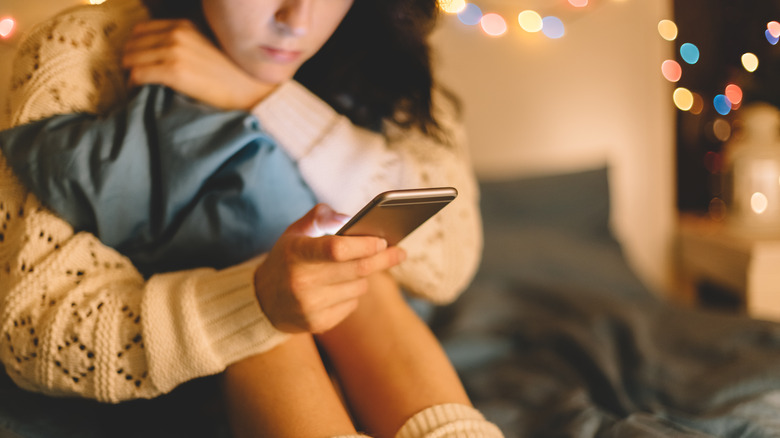 woman on bed with phone