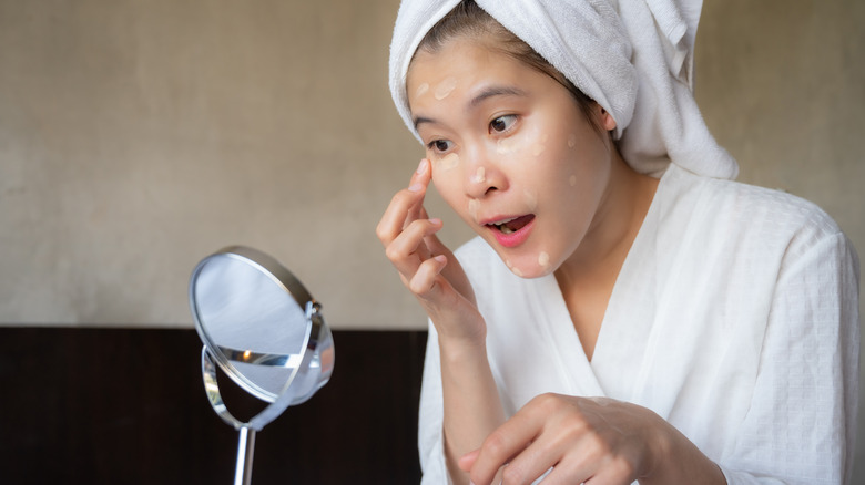 Woman applying concealer on face