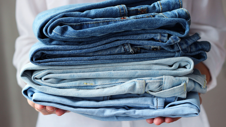 Person holding a stack of folded jeans