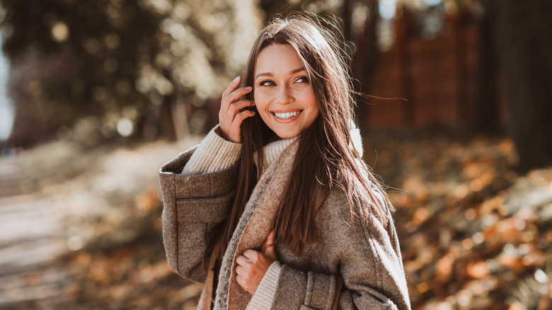 A woman smiles, posing in fall clothing