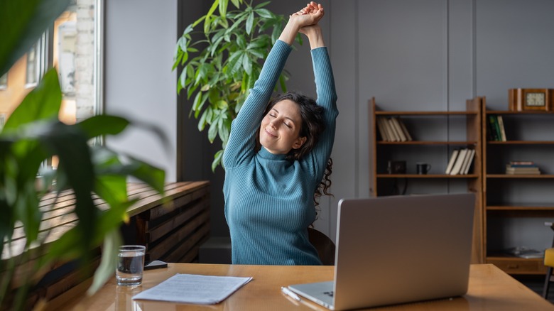 Happy woman stretching at desk
