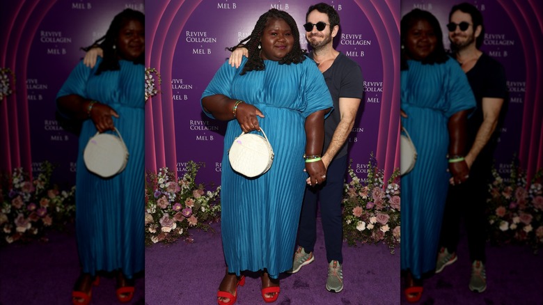 Gabourey Sidibe wearing a blue dress and red shoes poses alongside her husband Brandon Frankel