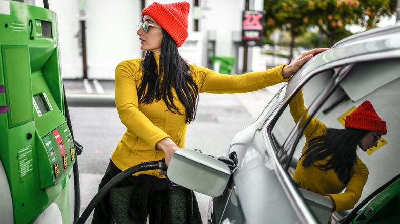 Woman wearing hat pumping gas