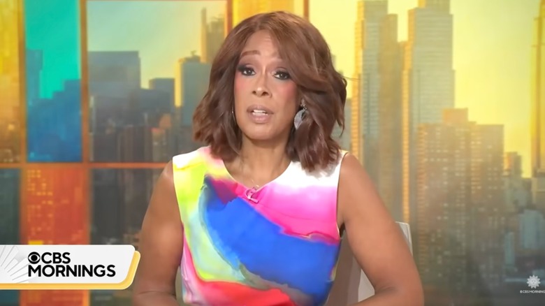 Gayle King wearing a white dress with neon patches of pink, blue, yellow, gray and red.