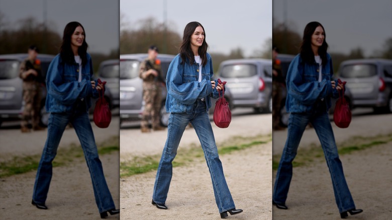 A woman walking in bootcut jeans and an oversized denim jacket