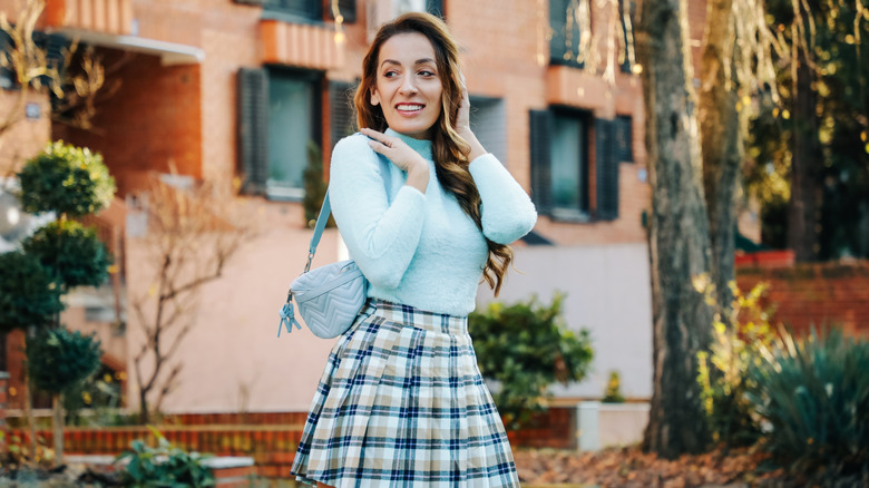 Woman wearing blue sweater and plaid skirt