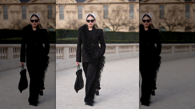 A woman wearing a black suit with feather trim