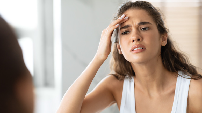 Young woman examining forehead wrinkles