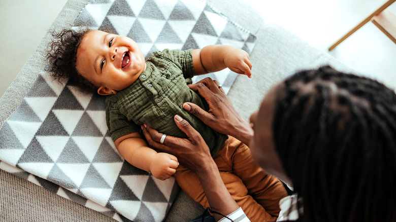 A mother tickling her laughing baby