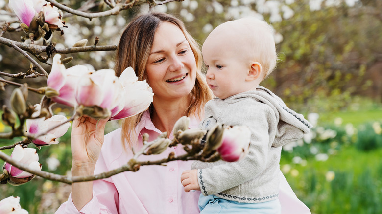 Mother holding her baby beside a flowering tree
