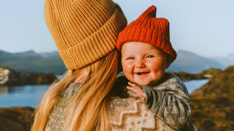 A mother and baby wearing beanie hats in the mountains