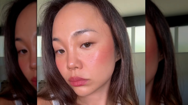 A woman wearing bright coral blush and lipstick